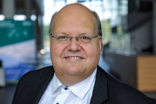 A person wearing glasses and a suit Description automatically generated