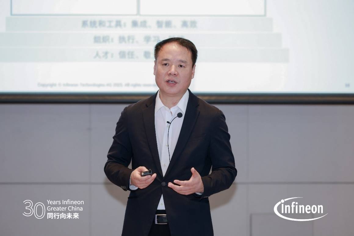 A person in a suit standing in front of a screen AI-generated content may be incorrect.
